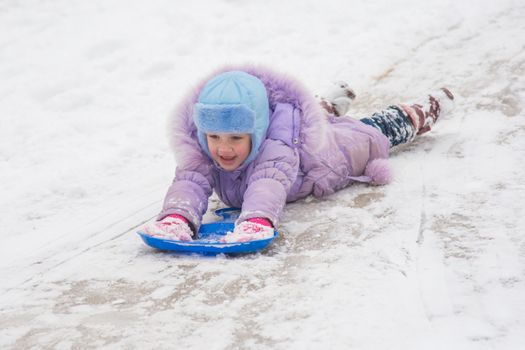 Five-year girl riding on a snowy icy hill