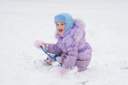 Five-year girl riding on a snowy icy hill