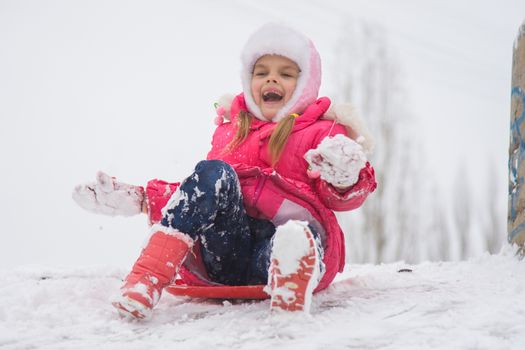 Seven-year girl riding on a snowy icy hill