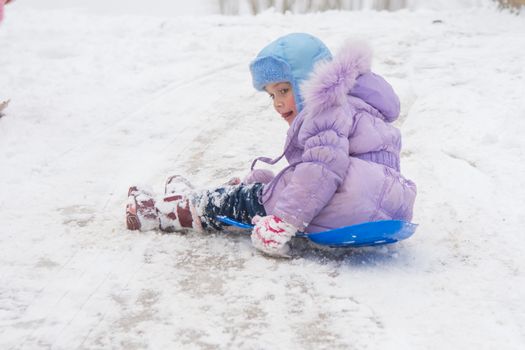 Seven-year girl riding on a snowy icy hill