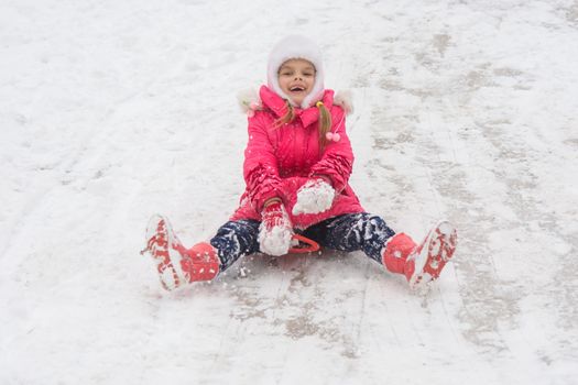 Seven-year girl riding on a snowy icy hill