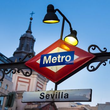 Detail of Vintage Sevilla Metro Station Sign in Madrid Spain, illuminated in dusk.