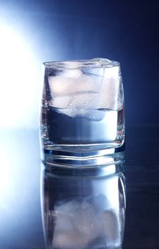 Glass of water with ice cubes on nice dark background