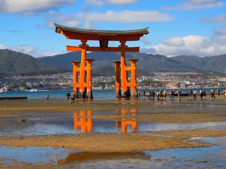 MIYAJIMA HIROSHIMA, JAPAN NOVEMBER 10, 2015: The famous orange floating shinto gate (Torii) of Itsukushima shrine panorama, Miyajima island of Hiroshima prefecture, Japan during low tide.