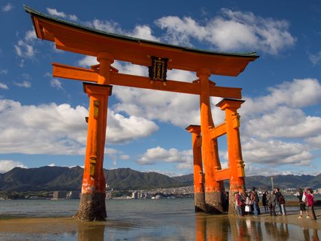 MIYAJIMA HIROSHIMA, JAPAN NOVEMBER 10, 2015: The famous orange floating shinto gate (Torii) of Itsukushima shrine panorama, Miyajima island of Hiroshima prefecture, Japan during low tide.