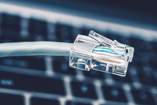 RJ45 Network Cable Connector Closeup with Keyboard in the Background.