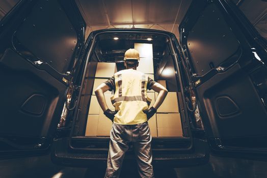 Cargo Van Delivery. Rear Cargo Doors Reloading. Construction Guy Talking Care of Fresh Supplies Delivery. Large Cargo Van with Many Cardboard  Boxes Waiting For Reload.