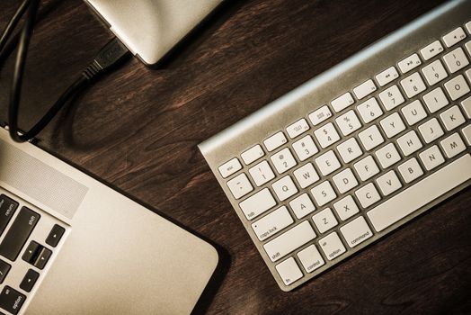 Entrepreneur Work Desk. Modern Working Desk. Laptop Computer, Wireless Keyboard and Portable External Drive. Dark Wooden Desk Top View