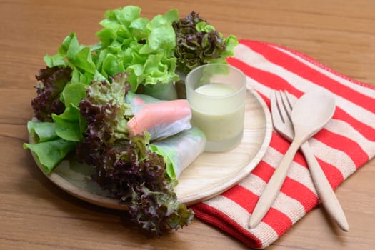 Salad roll vegetables and crab stick with salad dressing in wooden plate