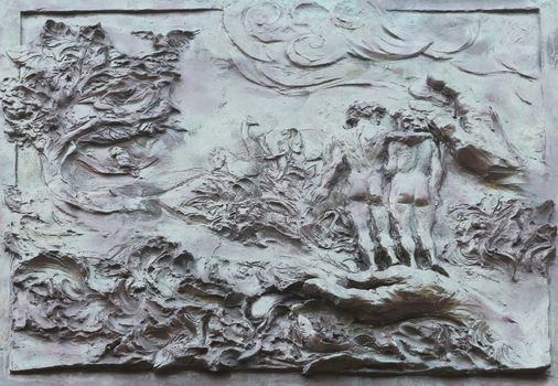 God Creating the Earth, Adam and Eve, detail on the door of the church of St. James the Greater in Porto Azzurro, Elba, Italy