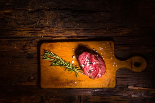 Raw beef steak on a dark wooden table.