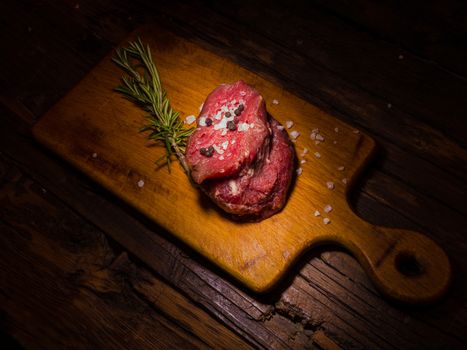 Raw beef steak on a dark wooden table.