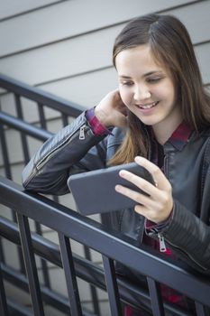 Pretty Smiling Young Girl on Staircase Looking at Smart Phone.