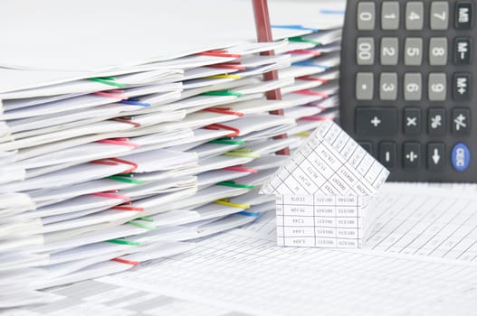 House with brown pencil place vertical on finance account have calculator and pile of document with colorful paperclip as background.