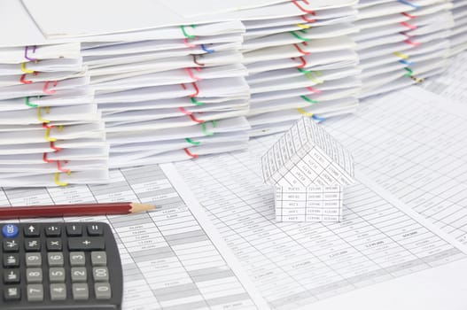 House with brown pencil and calculator on finance account have pile of document with colorful paperclip as background.