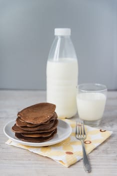 Chocolate pancakes with the glass and bottle of milk