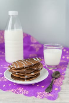 Chocolate pancakes with the glass and bottle of milk