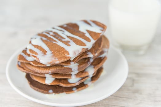 Chocolate pancakes with the glass of milk on the wooden table