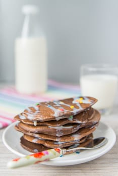 Decorated chocolate pancakes with the glass of milk on the coloured napkin