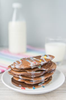 Decorated chocolate pancakes with the glass of milk on the coloured napkin