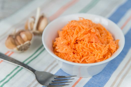 Carrot salad in the white plate with garlic