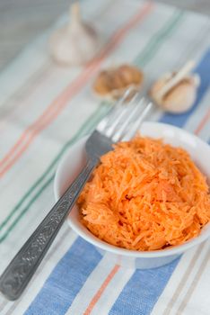 Carrot salad in the white plate with garlic