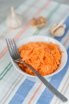 Carrot salad in the white plate with garlic and fork
