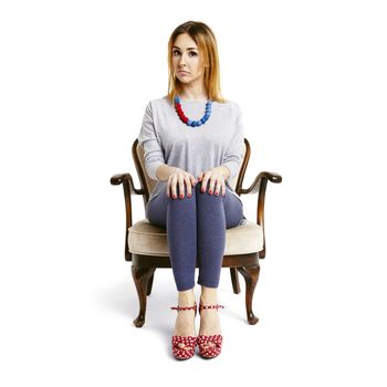 Studio shot of serious woman sitting on armchair. Isolated on white.