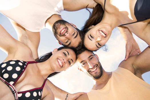 Multicultural group of friends embraced together at the beach 