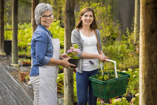 Beautiful mature florist helping a female customer to choose plants