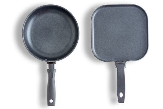 Two round and square with chamfered corners clean pans or skillets on a white background arranged side by side and viewed from above in a cookery concept