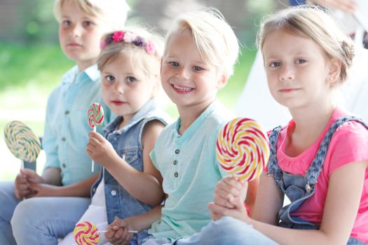 Group of happy smiling children with lollipops outdoors