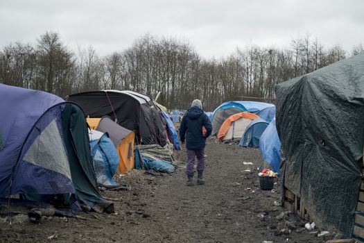 FRANCE, Grande-Synthe: A migrant is seen walking in the mud in the camp in Grande-Synthe, northern France on January 29, 2016.