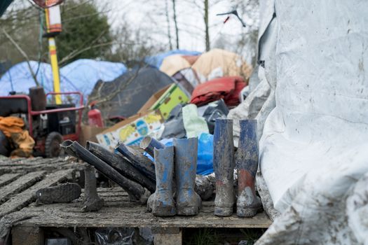 FRANCE, Grande-Synthe: Muddy boots are seen sitting next to a tent in the camp in Grande-Synthe, northern France on January 29, 2016.