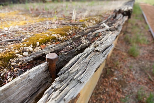 closeup of a rusted bolt in rotting timber at a disused railway station.