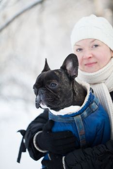 French bulldog in the arms of a woman in winter