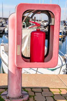 Red fire extinguisher in box on dock railing. 