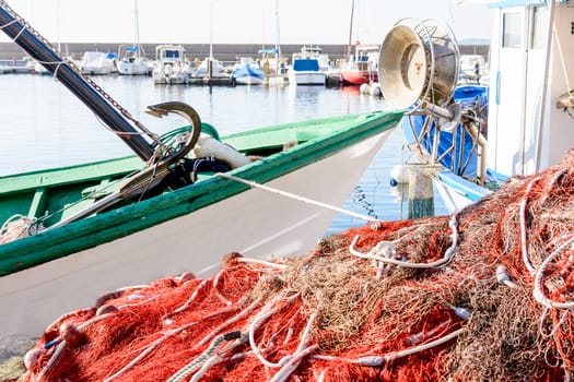 Red fishing on pier and on the boat. Fishing net and boats waiting for the small marina.