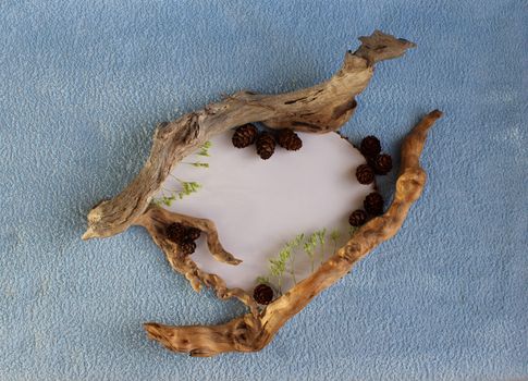 A heart frame of larch cones and dry sticks on a blue and white background.