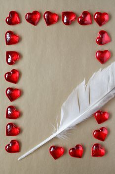 Love concept. Quill pen and red hearts as frame on paper background