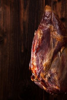 Traditional smoked meat hanging against wooden background. Culinary meat eating. 