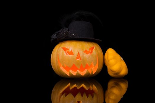 Creepy halloween pumpkin with hat isolated on black background. Traditional american halloween decoration.