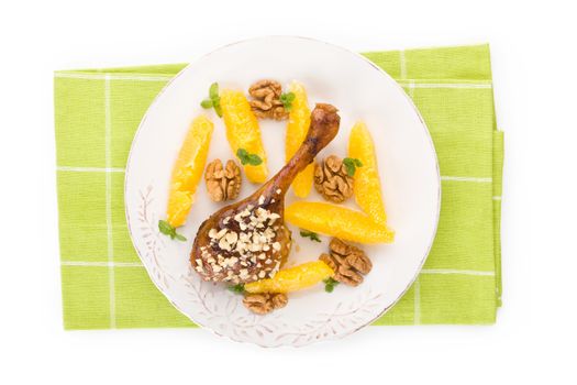 Culinary roast duck with oranges and nuts on plate isolated on white background. Flat lay, top view. Delicious festive eating. 