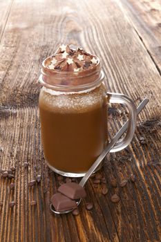 Hot chocolate with coffee beans and chocolate on wooden table. Delicious cocoa drink.