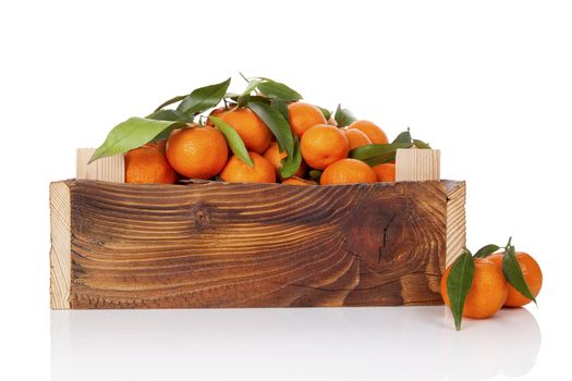 Fresh ripe mandarines with green leaves in wooden crate. Organic fresh mandarines, healthy fruit eating. 