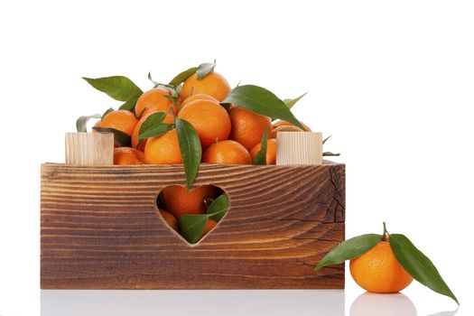 Fresh ripe mandarines with green leaves in wooden crate. Organic fresh mandarines, healthy fruit eating. 