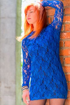 female 30 years, in a lace dress posing near the wall