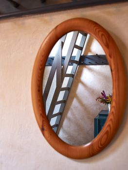 Classical vintage oval wooden mirror with reflection of a staircase