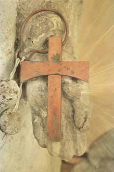 An old rusty cross in a holy hand with glowing rays.