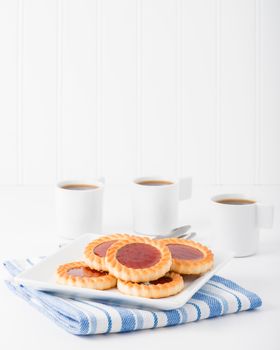 Plate of jam filled biscuits served with coffee.